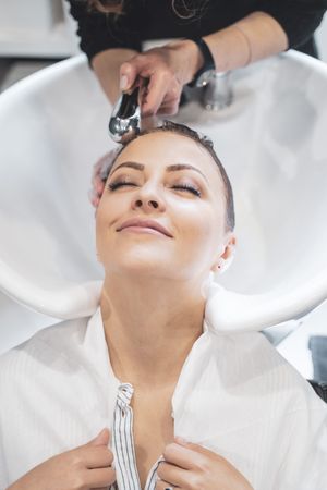 Stylist washing hairs to young woman