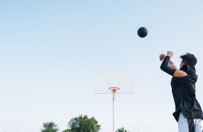 Young man playing on yellow basketball court outdoor.
