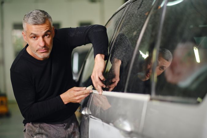 Mechanic putting protective tape on car