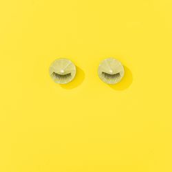 Lime fruit with eyelashes on bright yellow background