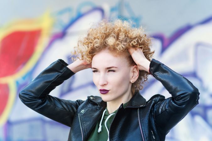 Portrait of fashionable female with curly hairstyle and violet lipstick wearing a rock style