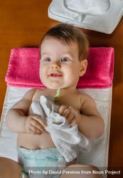 Cute baby playing with towel during diaper change, vertical 4dOvn5