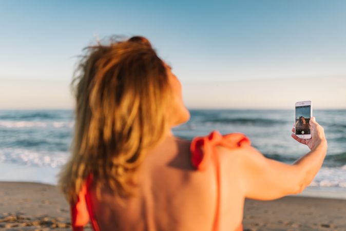 Woman in red dress taking photo on smartphone