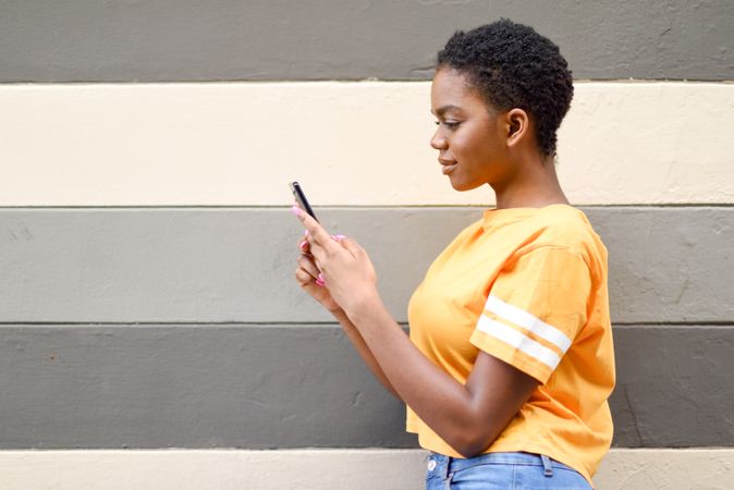 Female checking phone in front of striped wall