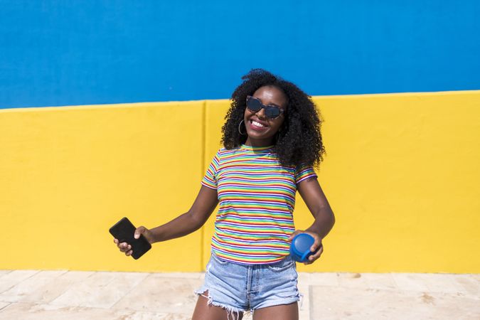 Black woman smiling in front of bright yellow and blue wall