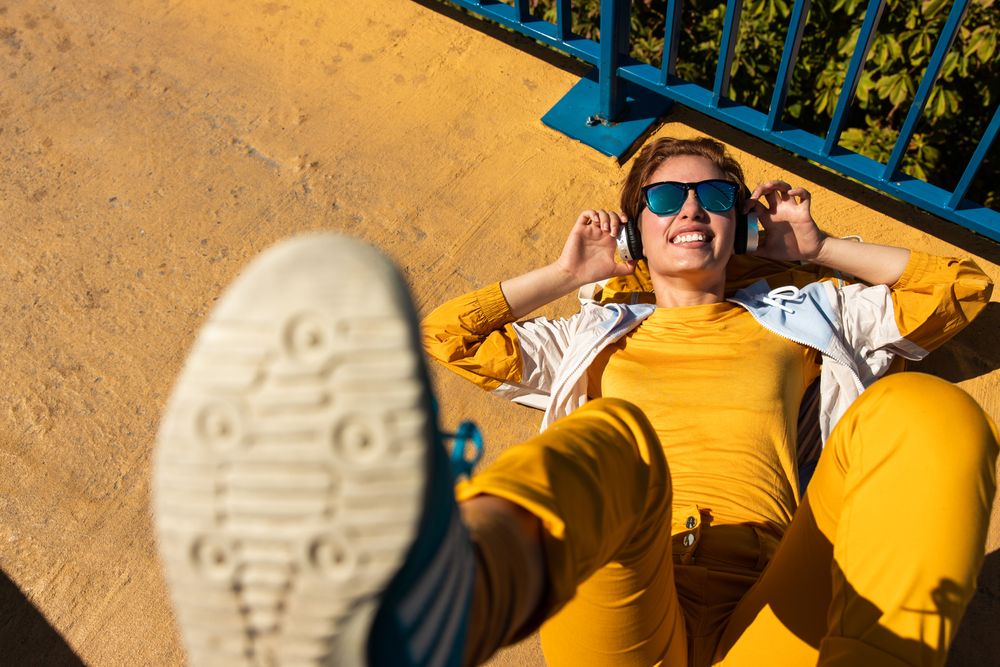 Stylish young woman in vibrant clothes enjoying music on street
