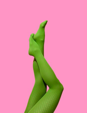 Woman legs in green tights isolated on a pink background