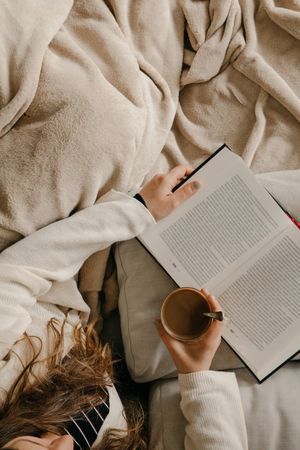 Person reading a book on the bed