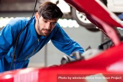 Man looking at open engine of red car auto repair shop 0gn3Ab