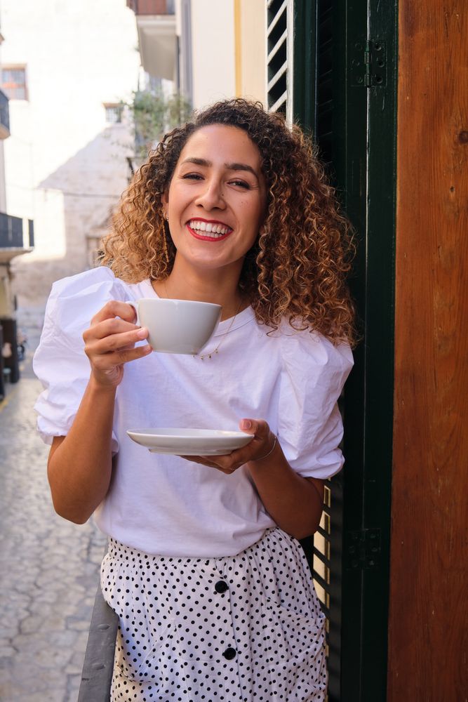 Smiling woman drinking coffee and looking at camera