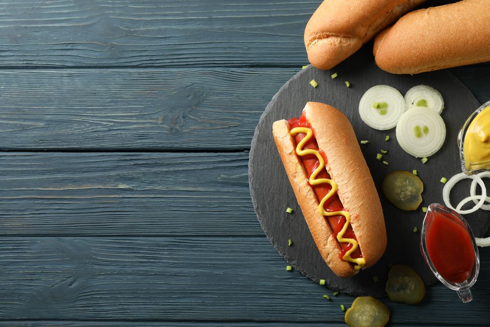Tasty hot dog and ingredients on wooden background