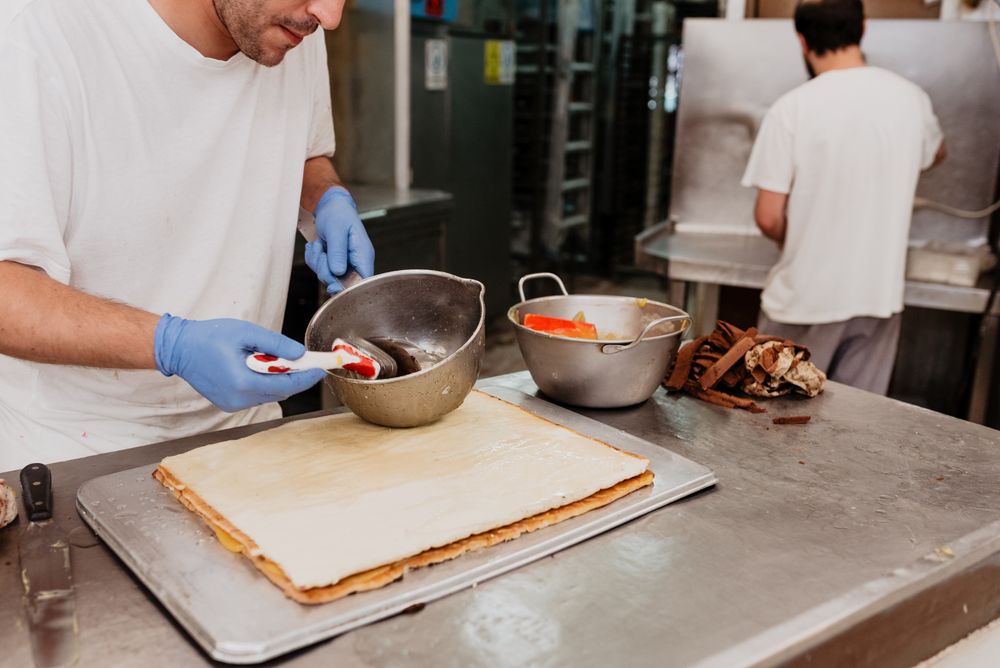 Crop confectioner smearing jam on croissant