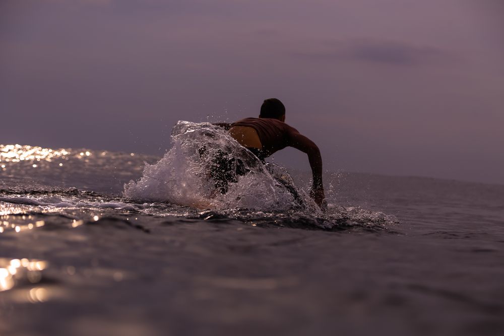 Man on surf board floating on water and cloudy sky