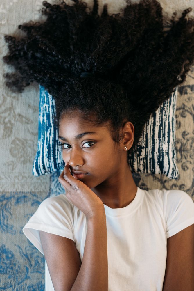 Beautiful young Black teenage girl lying down in a rug