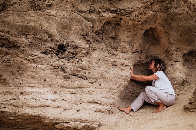 Barefoot woman meditating in rock cavity