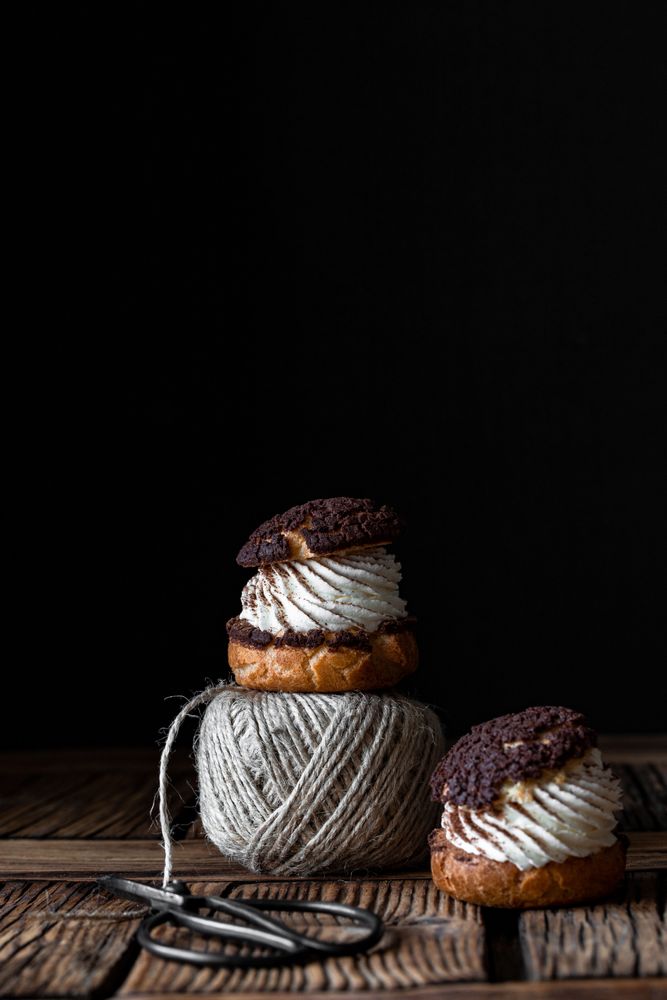 Delicious choux buns and wool threads on wooden table