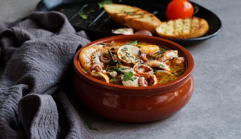 Soup of octopus and shrimps near toasts and spoon