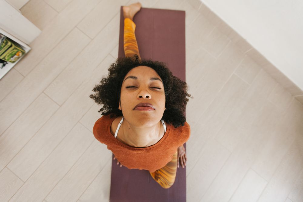Sportive woman performing yoga pose in room