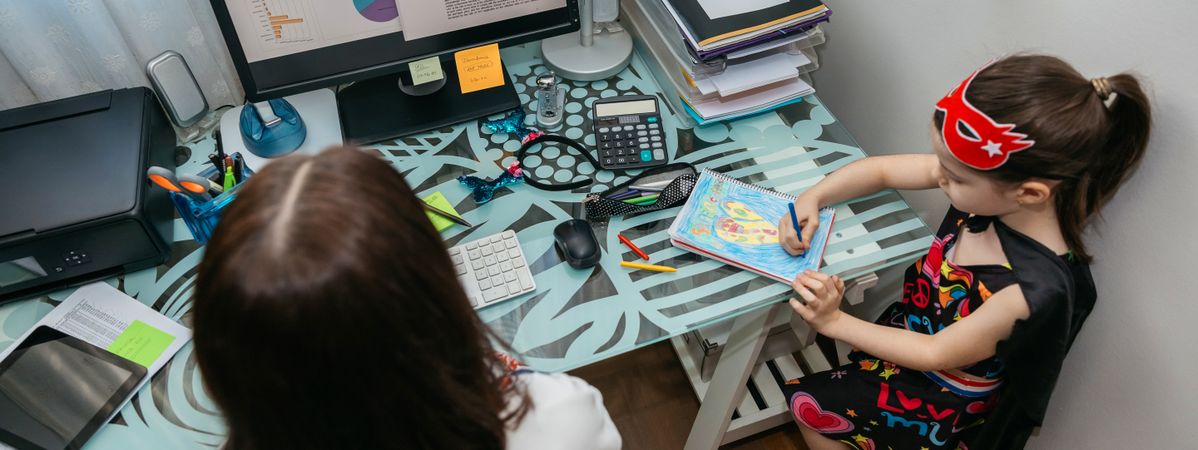 Woman teleworking with her daughter drawing