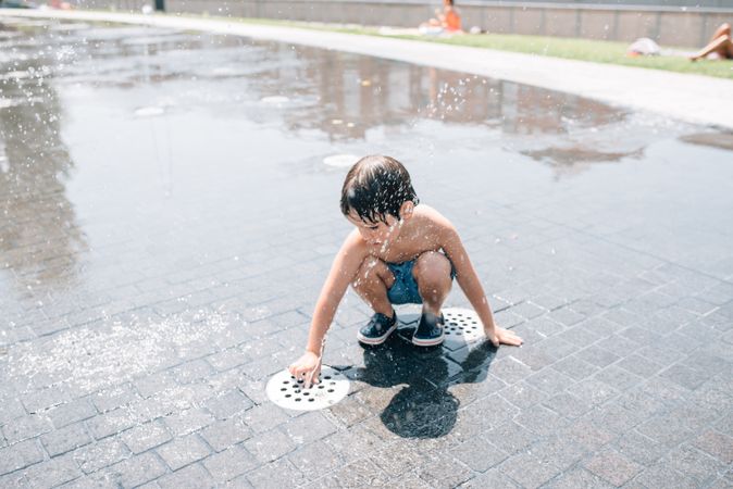 Kid standing in jet of fountain on street