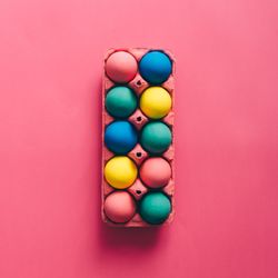 Colorful Easter eggs in box on pink background