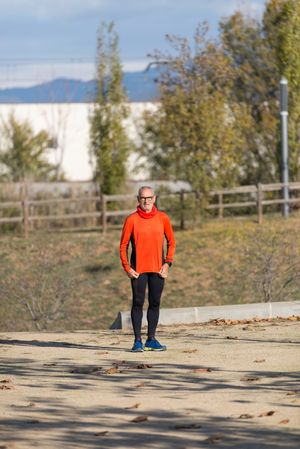 Older man in leggings and windbreaker standing in park