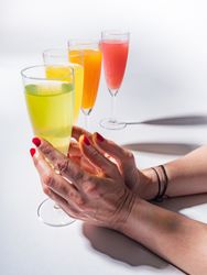 Hand and glasses of bright colorful drinks on table