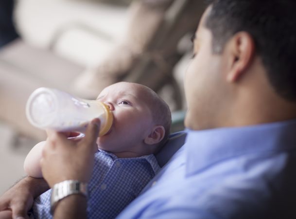 Happy Hispanic Father Bottle Feeding His Son