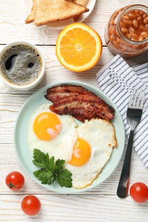 Vertical shot of full breakfast with eggs, beans, bacon, fruit and coffee