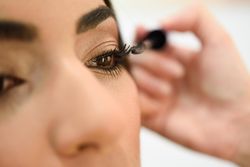 Woman applying mascara to client’s face