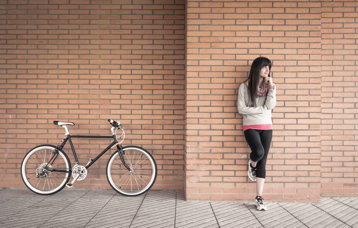 Sportive woman with fixie bike over a brick wall