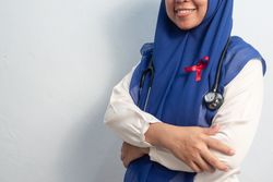 Close up Muslim Female Asian doctor or nurse wearing Red ribbons on cloth, HIV awareness concept, world AIDS day, world cancer day.