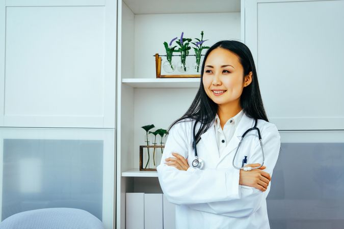 Proud Asian doctor in her clinic with arms crossed