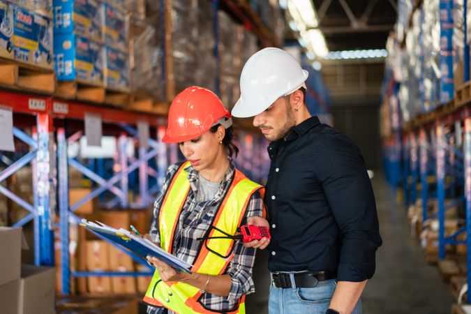 Male and female logistics workers checking stock distribution before shipping