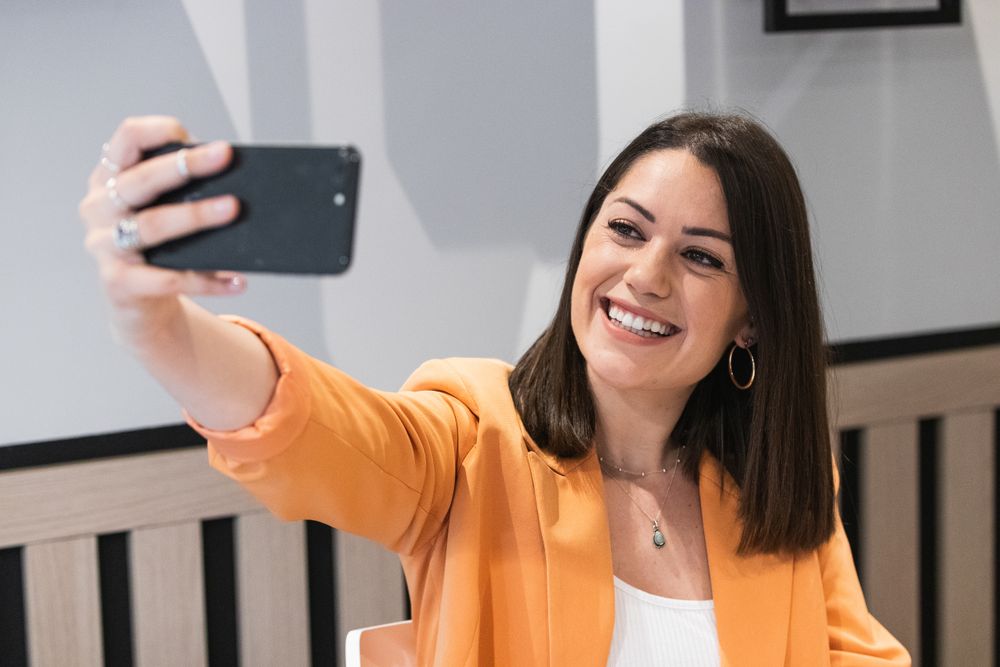 Cheerful woman taking selfie on smartphone in cafe