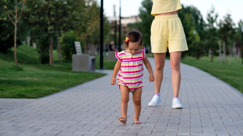 Toddler girl and mother walking on path