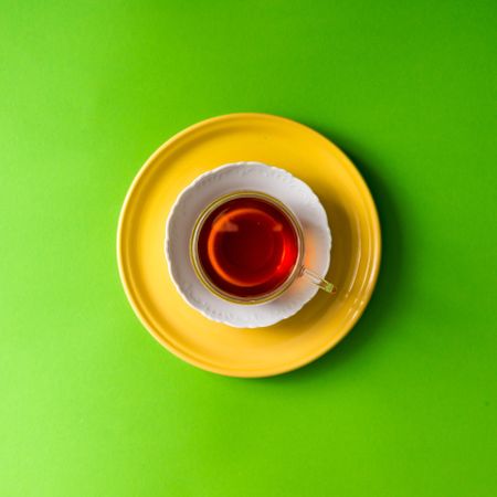 Tea in glass cup on green background