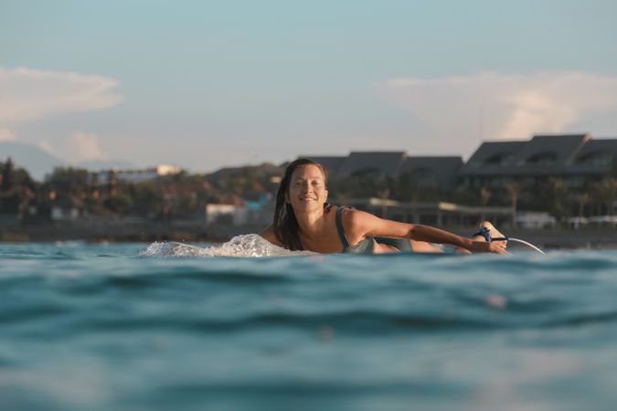 Smiling woman on surf board floating on water