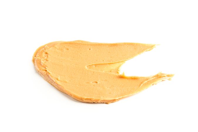 Creamy peanut butter isolated on bright background. A traditional product of American cuisine