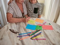 Unrecognizable grandmother and boy drawing on paper