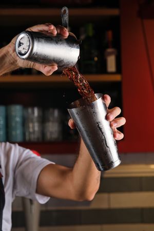 Unrecognizable barman mixing drink in pub