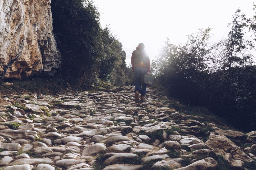 Woman with case walking on rocks above stream