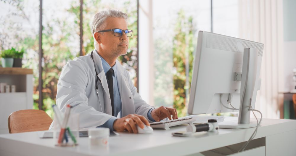 Portrait of a Medical Health Care Professional Working on Desktop Computer in Hospital Office.