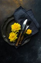 Dark table setting with yellow roses and chopsticks