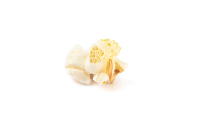 Piece of popcorn isolated on blank background, close up