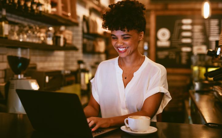 Smiling female cafe owner using laptop