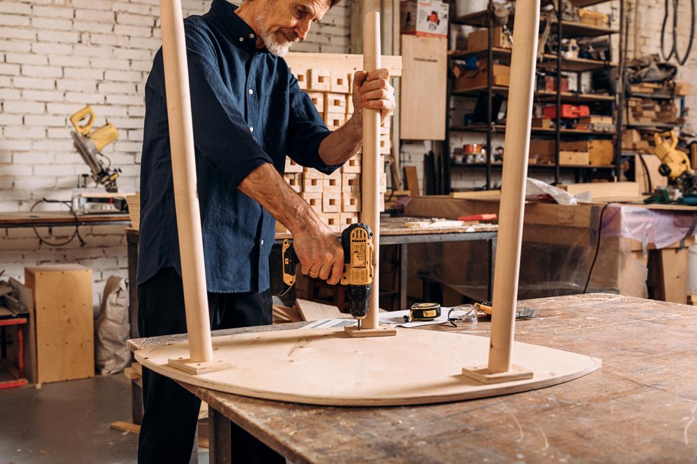 Man building table with power tools in woodworking shop