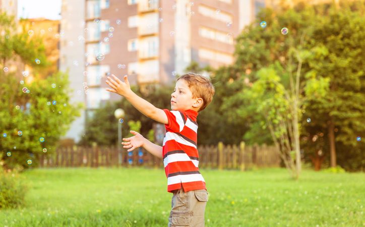 Happy boy playing with soap bubbles in the park