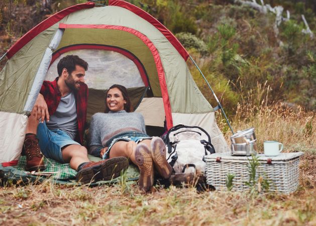 Happy young couple sitting in a camping tent