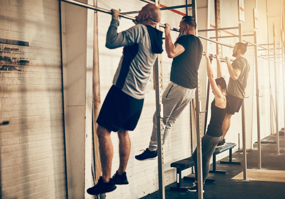 Group of people doing chin ups in gym class